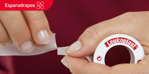 Miniatura de uma pessoa a cortar a fita adesiva para uma ferida Miniatura de uma pessoa a cortar a fita adesiva para uma ferida
